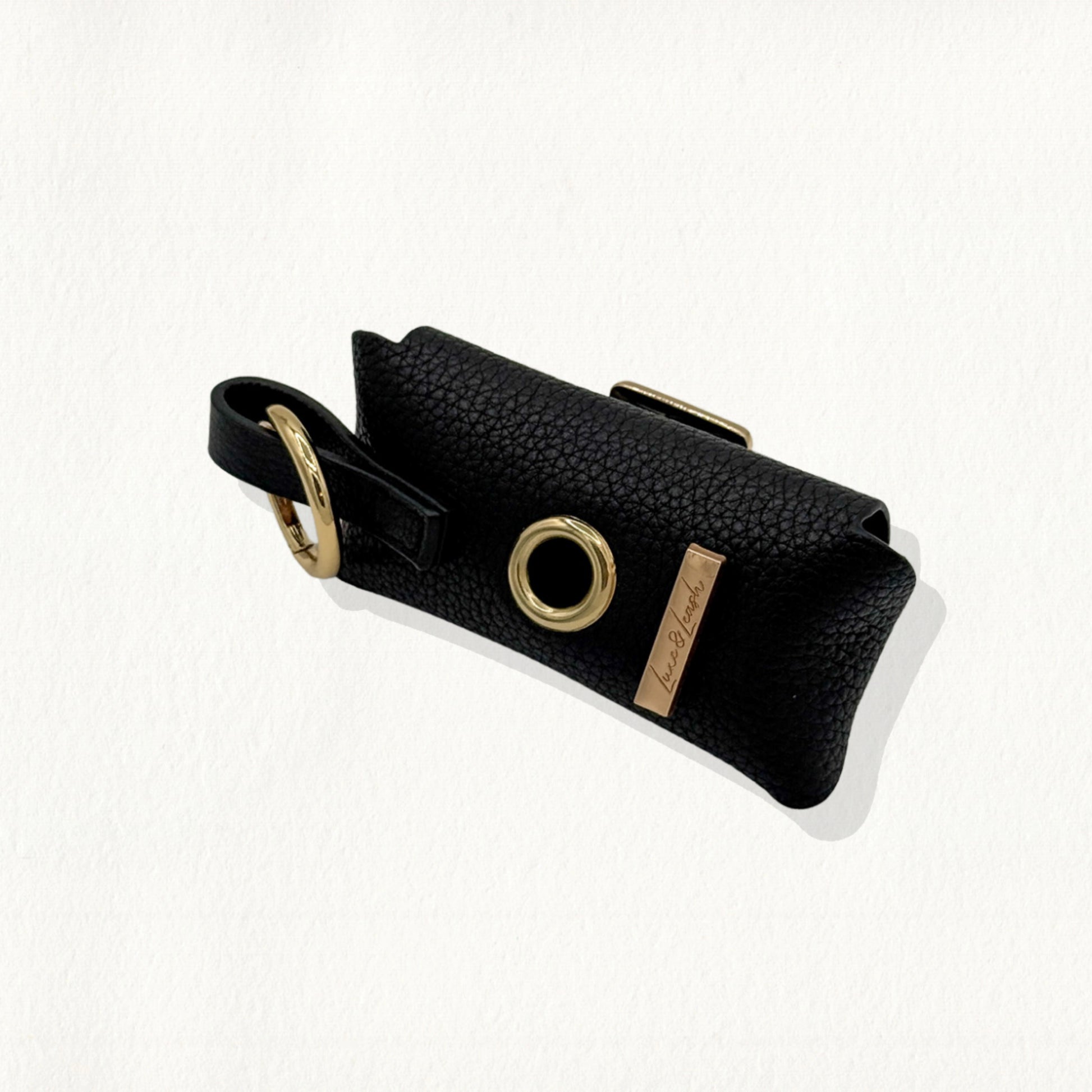 Noir leather waste bag dispenser with a gold-rimmed dispensing hole.