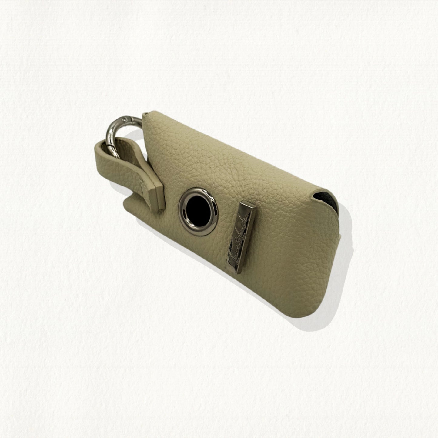 Sandstone leather waste bag dispenser with a gold-rimmed dispensing hole.