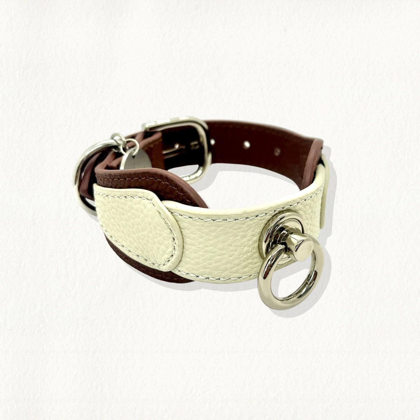Side view of a white and brown layered leather dog collar with silver-toned hardware and stitching.