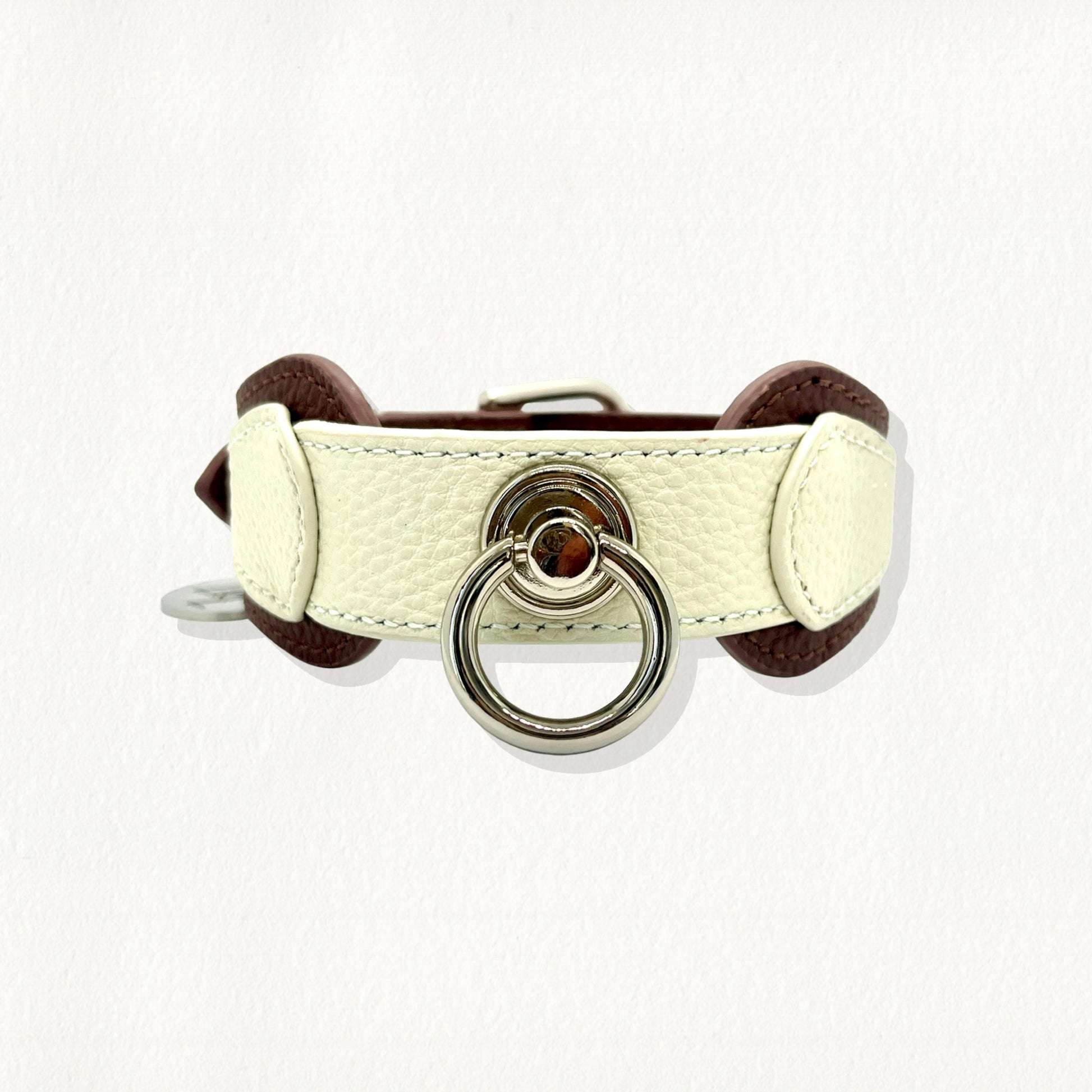 Front view of a dual-toned white and brown pebbled leather dog collar with a large silver decorative ring.