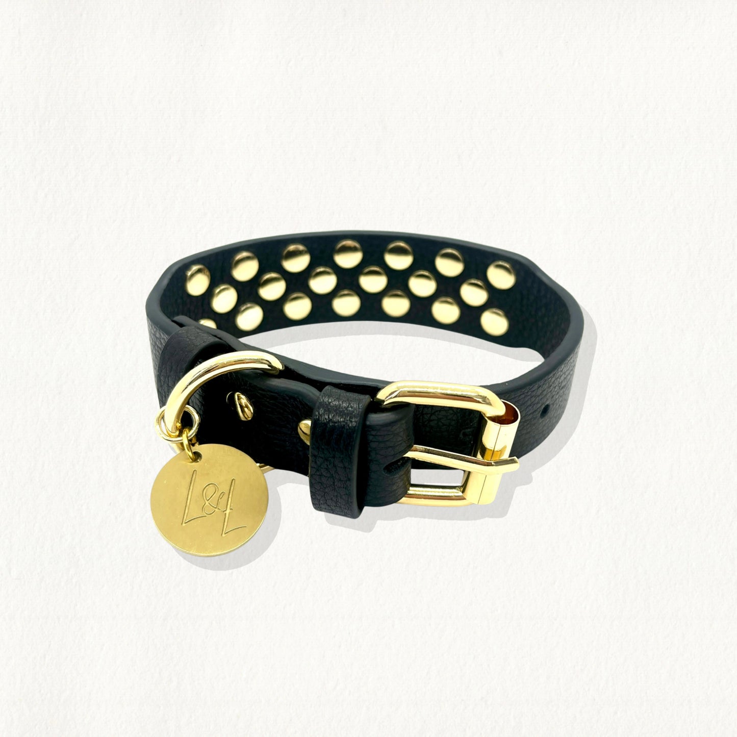 Top-down view of a studded black leather dog collar with polished gold hardware and branding.